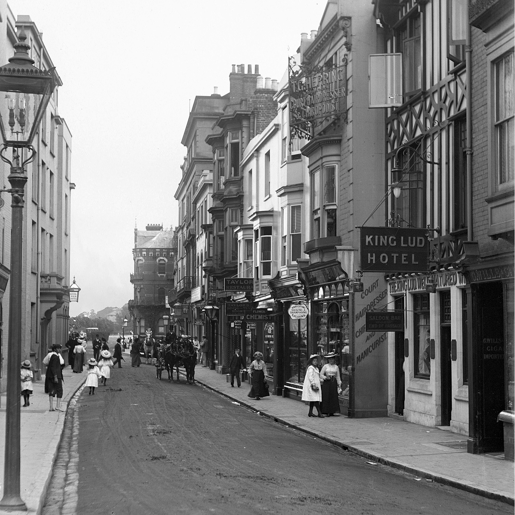 This is Pier Street in 1913. On the left is the side of the Royal Pier Hotel and on the right, the King Lud with its mock Tudor front.