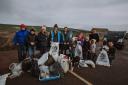 Volunteers with their bags of rubbish after the beach clean Photography by Little Isle Photography.