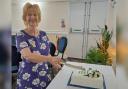 Chair Corinne Halkyard cutting the celebratory cake for West Wight Floral Arts Society