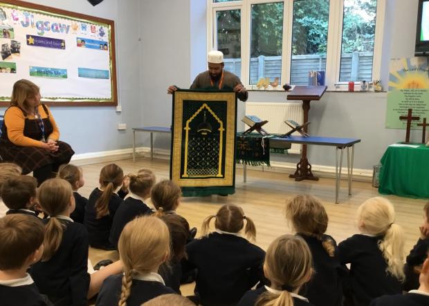 Isle of Wight County Press: Muhammed Bahar showing pupils a prayer mat, Brighstone Primary School