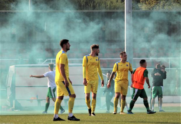Isle of Wight County Press: Dejected Newport players shellshocked at full time, amid the green smoke of a flare set off by Laverstock fans. Photo: Graham Brown