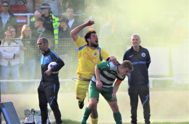 Isle of Wight County Press: Newport captain Martin McDonough in yellow trying to follow the ball amid green smoke from a flare.  Photo: Graham Brown
