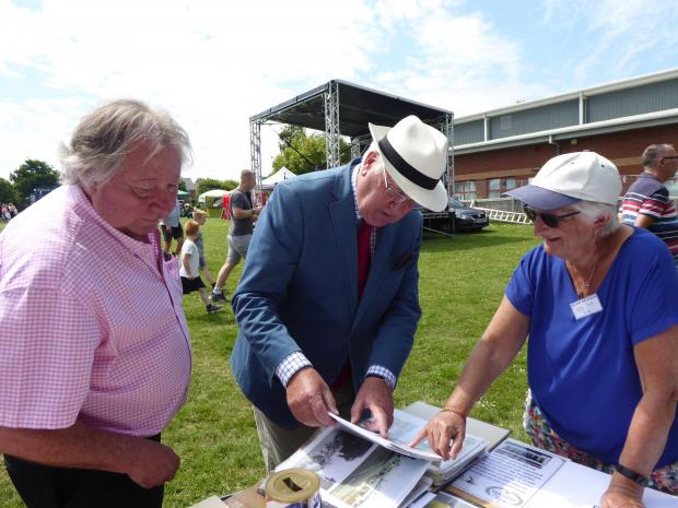 Isle of Wight County Press: The West Wight Heritage Centre display at the jubilee event in Freshwater on June 3. The Vice Lord-Lieutenant Brigadier Maurice Sheen looks at old photos with Cllr George Cameron and Rose Stanley (Freshwater & Totland Archive Group Treasurer).