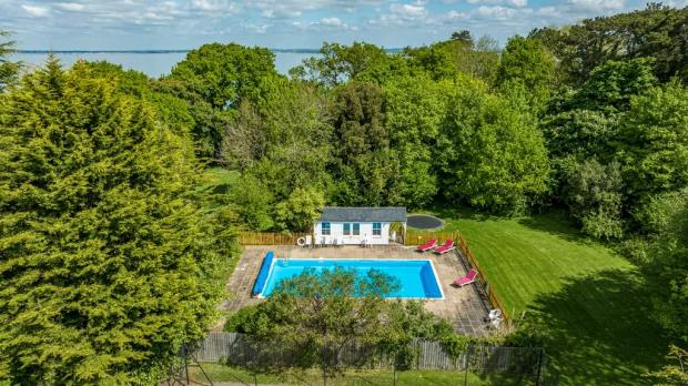Isle of Wight County Press: The heated swimming pool is enclosed by fencing and boasts a paved terrace and pool house. Picture: Zoopla